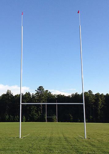 Professional rugby goal posts with red flags against a clear sky