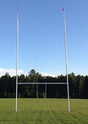 Professional rugby goal posts with red flags against a clear sky