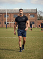 Ruggers Rugby Supply KooGa black compression top worn by a man on a rugby pitch with raglan sleeves and moisture-wicking fabric.