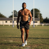 Ruggers Rugby Supply athlete wearing black KooGa ProK rugby shorts on a field with goalposts in the background