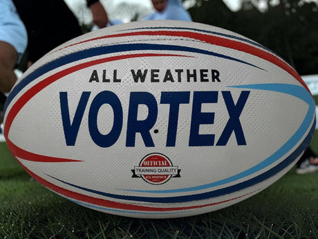 Ruggers Rugby Supply KooGa Vortex all-weather rugby practice ball with red and blue graphic details on a grass pitch